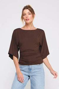 Woman wearing a double knit angel sleeve cinch side top with light wash jeans