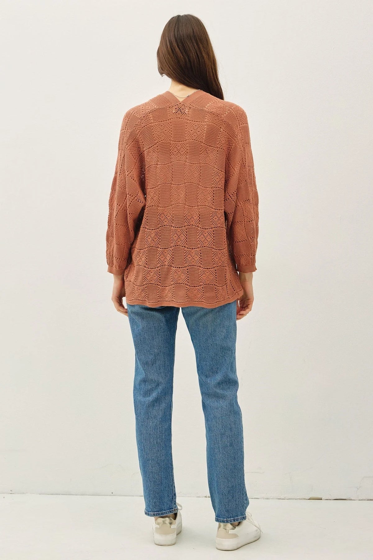 Woman wearing a crochet knit cardigan in brown and blue jeans showcasing the crochet knit cardigan