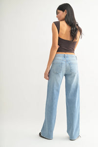 Woman showcasing low slung vintage straight denim jeans with a brown top