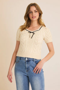 Woman in a cream cable-knit tie cable sweater with square neck puff half sleeves
