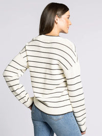 Woman wearing a cream-colored supply IRA sweater with blue jeans, fashionable and cozy
