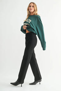 Woman modeling dark green patch pocket flare jeans with black pointed-toe boots