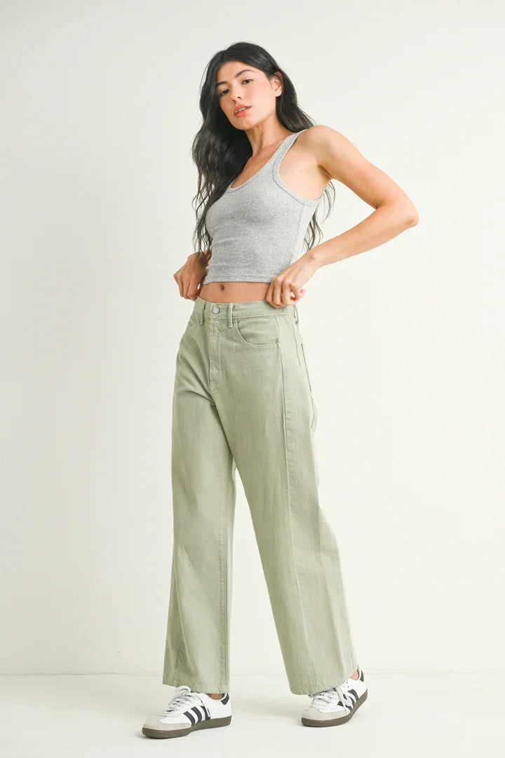 Woman in gray tank top and green pants showcasing High Rise Barrel Denim Jean Twist from Shop Daisy