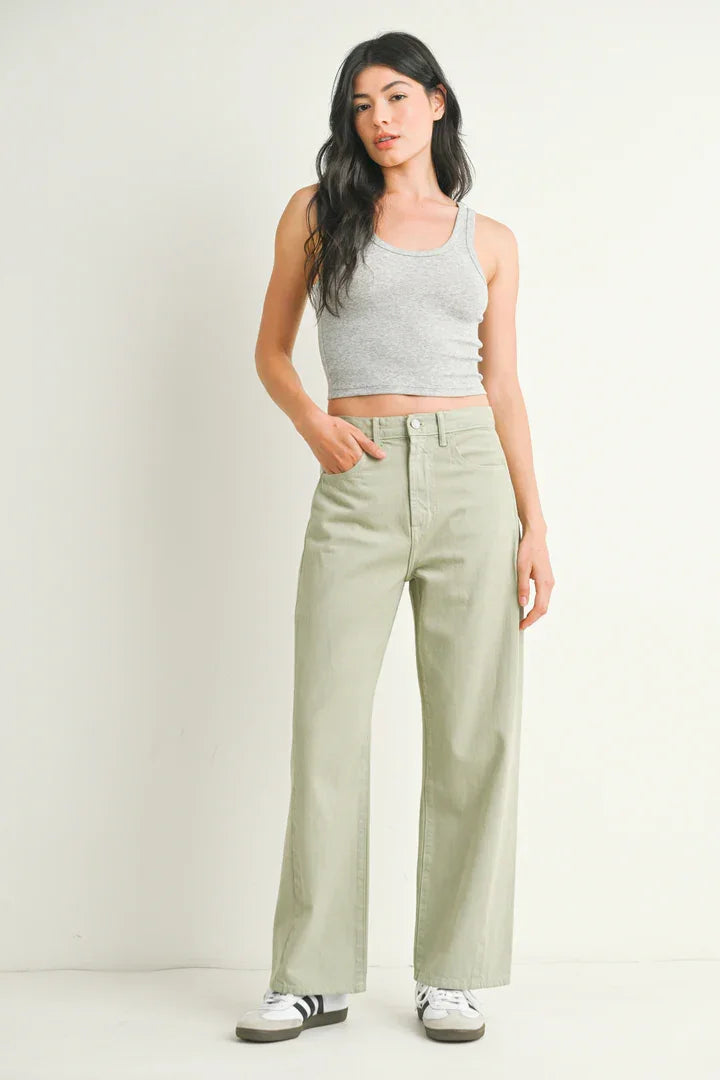 Woman in gray tank top and green pants showcasing HIGH RISE BARREL DENIM JEAN TWIST from Shop Daisy