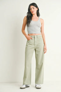 Woman in gray tank top and green pants showcasing HIGH RISE BARREL DENIM JEAN TWIST from Shop Daisy