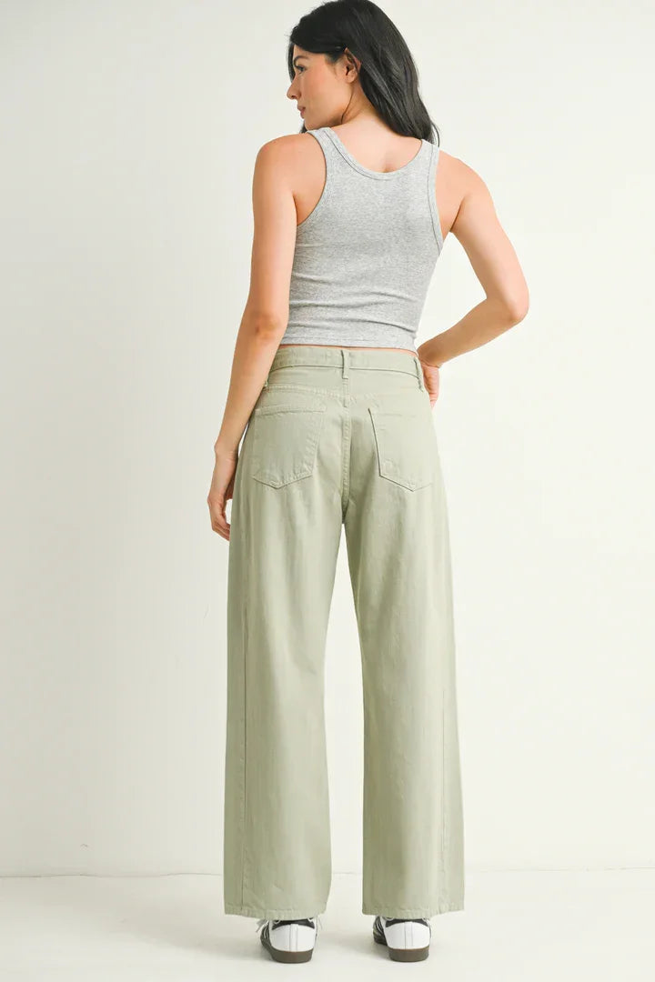 Woman in gray tank top and green wide-leg pants, showcasing jeans from Shop Daisy