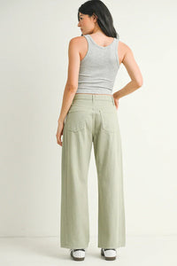 Woman in gray tank top and green wide-leg pants, showcasing jeans from Shop Daisy