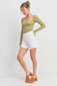 Woman in green top and white shorts showcasing SUMMER BOYFRIEND SHORT, perfect for women’s boho chic clothing from Shop Daisy