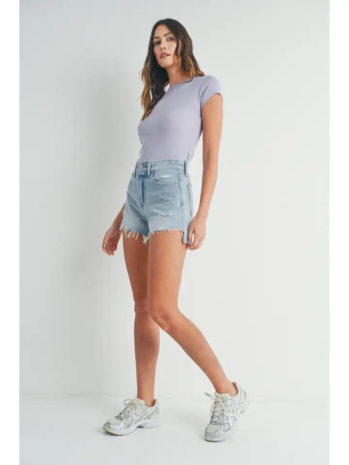 Woman in lavender top and denim shorts showcasing Vintage Frayed Hem Short Denim