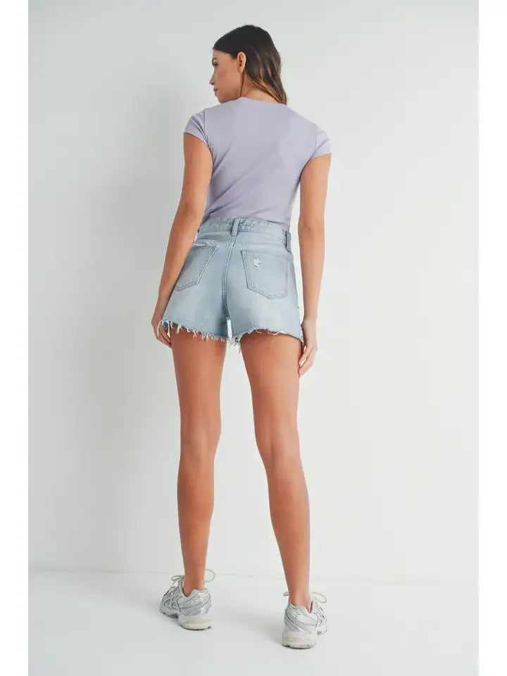Woman in lavender t-shirt and denim shorts featuring vintage frayed hem style