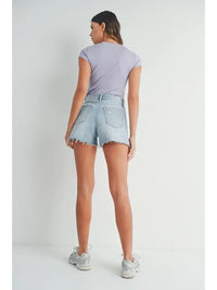 Woman in lavender t-shirt and denim shorts featuring vintage frayed hem style