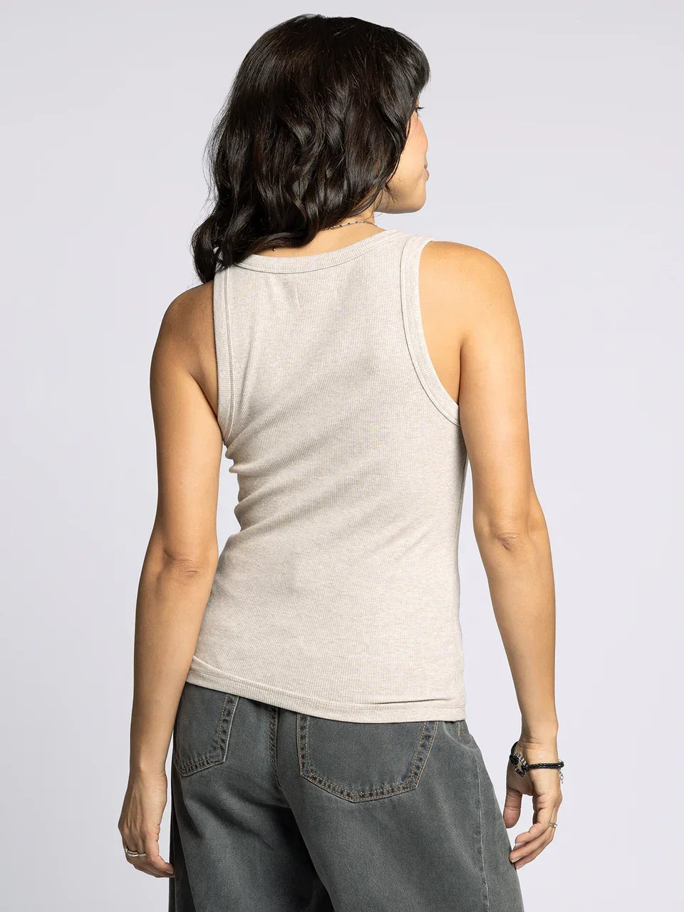 Woman modeling the Edlin Basic Tank in light beige with dark grey wide-leg pants