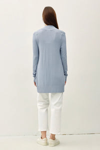 Woman wearing a light blue cotton blend knit open front cardigan and white pants