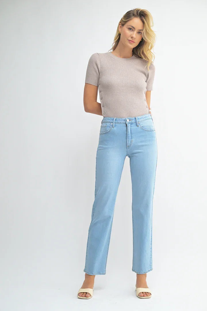 Woman wearing light blue jeans from Shop Daisy’s mid rise waist classic straight leg denim collection, perfect for women’s boho chic clothing