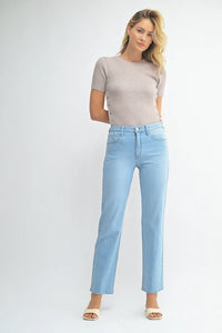 Woman wearing light blue jeans from Shop Daisy’s mid rise waist classic straight leg denim collection, perfect for women’s boho chic clothing