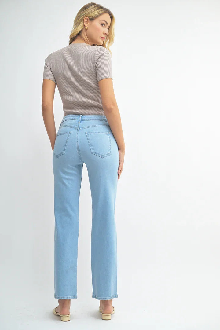 Woman wearing light blue jeans from MID RISE WAIST WITH A CLASSIC STRAIGHT LEG CUT DENIM JEANS, perfect for women’s boho chic clothing. Shop