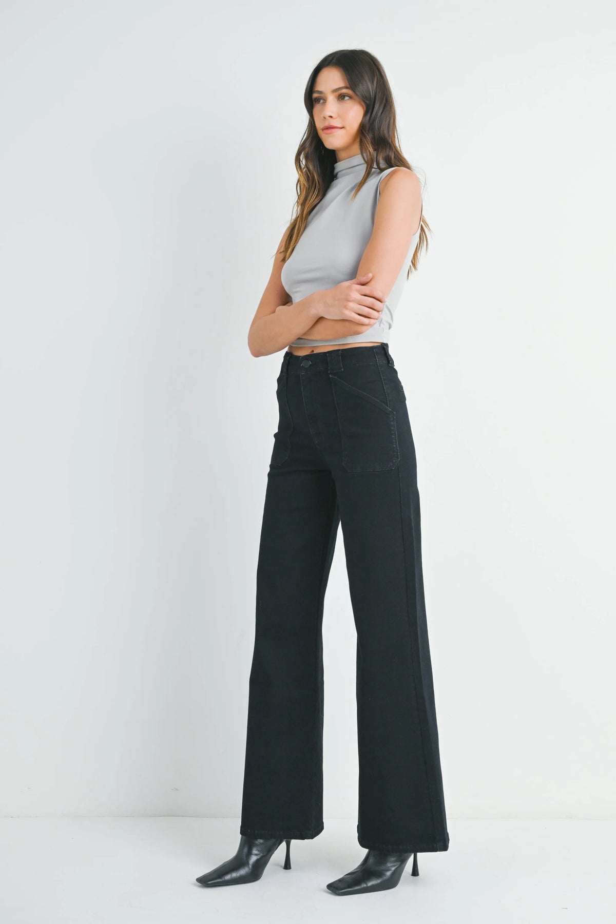 Woman wearing light gray sleeveless mock neck top with patch pocket wide flare denim jeans