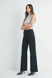 Woman wearing light gray sleeveless mock neck top with patch pocket wide flare denim jeans