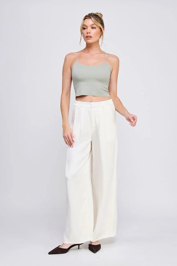 Woman wearing a light green smooth rib bralette tank with laser cut back detail