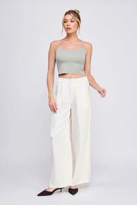 Woman wearing a light green smooth rib bralette tank with laser cut back detail