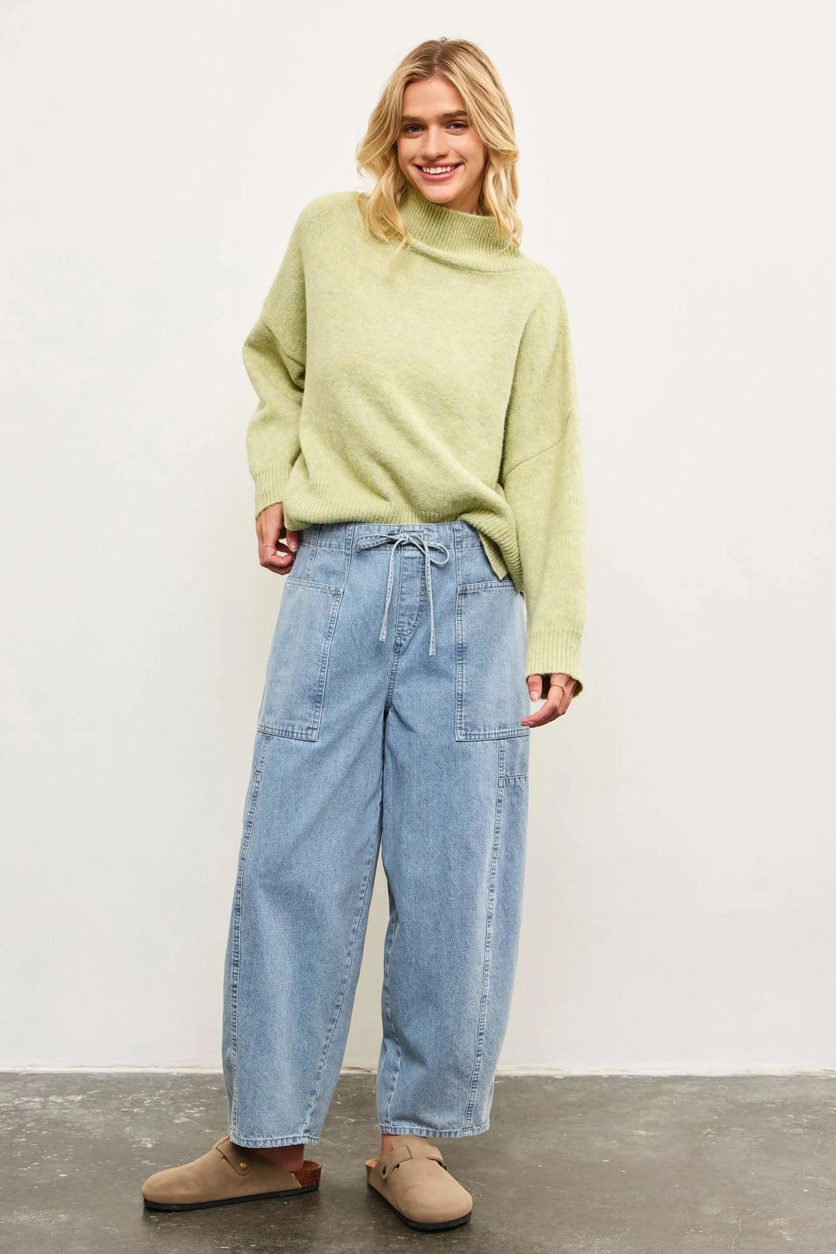 Woman wearing light green sweater and blue drawstring pants in women’s boho chic clothing