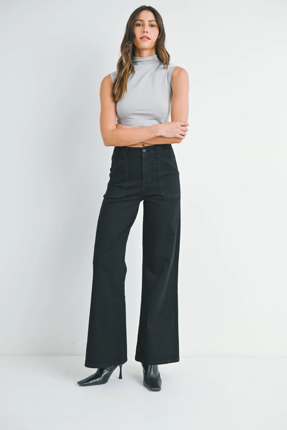 Woman wearing high rise patch pocket wide leg flare denim jeans and light grey sleeveless top