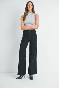 Woman wearing high rise patch pocket wide leg flare denim jeans and light grey sleeveless top