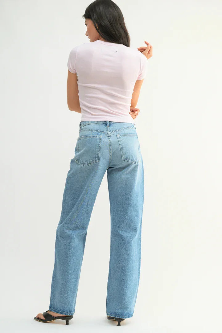 Woman in light-wash straight leg jeans paired with a pink top, featured in Shop Daisy