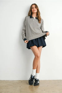 Woman wearing a striped collared long sleeve polo shirt and dark bubble skirt