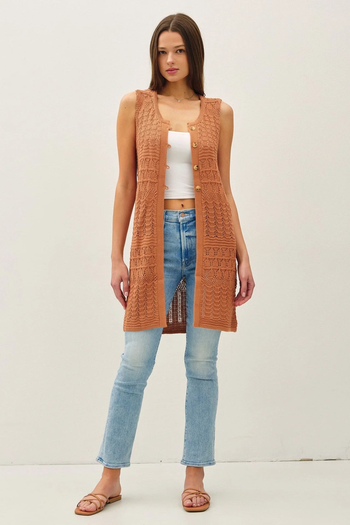 Woman wearing a crochet knit long sleeveless boho chic duster from Shop Daisy