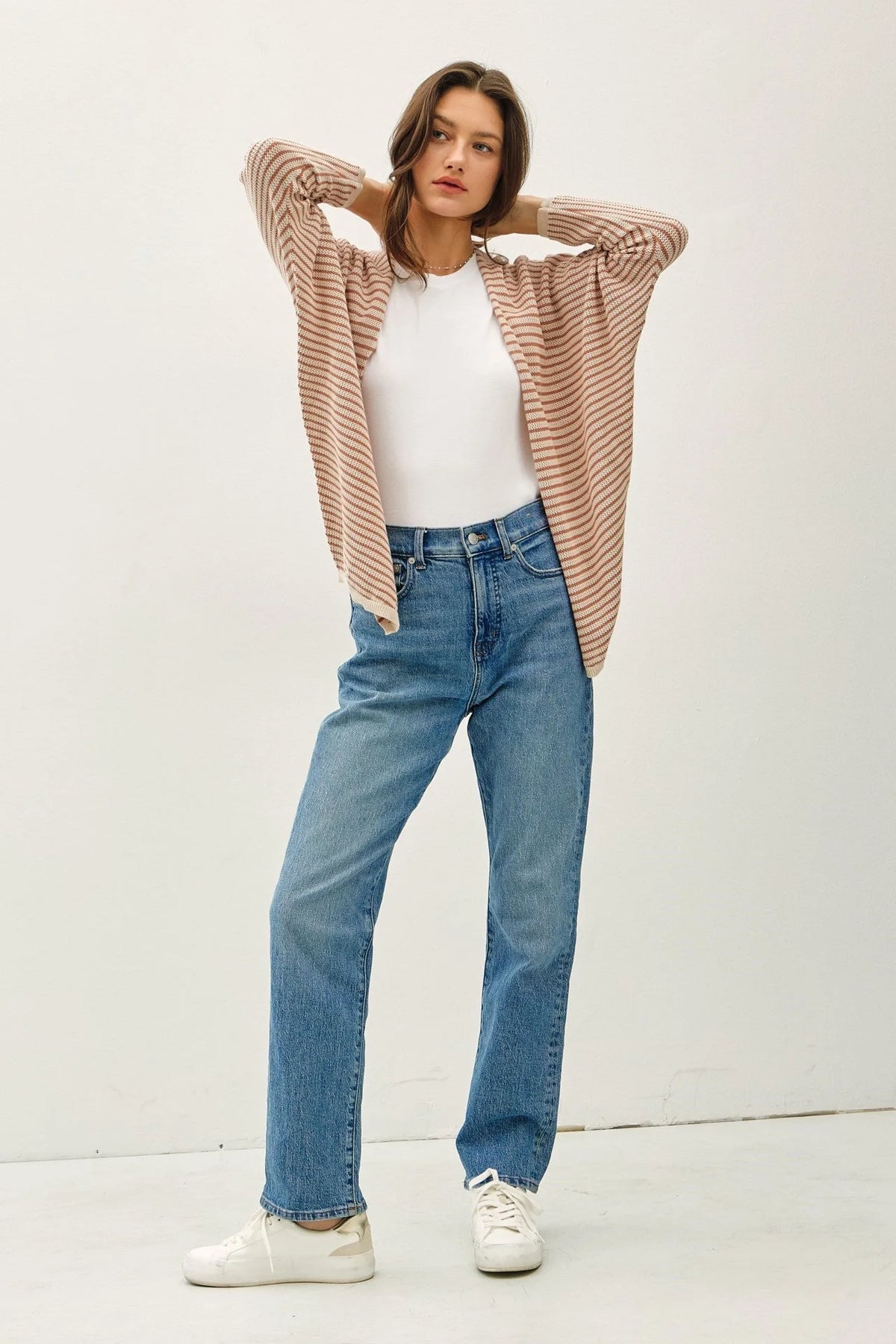 Woman wearing beige and white striped dolman sleeve open cardigan with white t-shirt and blue jeans