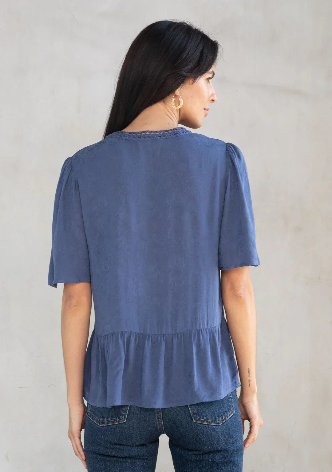 Woman modeling floral jacquard airy short sleeve peplum blouse with dark wash jeans