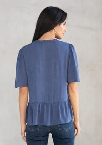 Woman modeling floral jacquard airy short sleeve peplum blouse with dark wash jeans