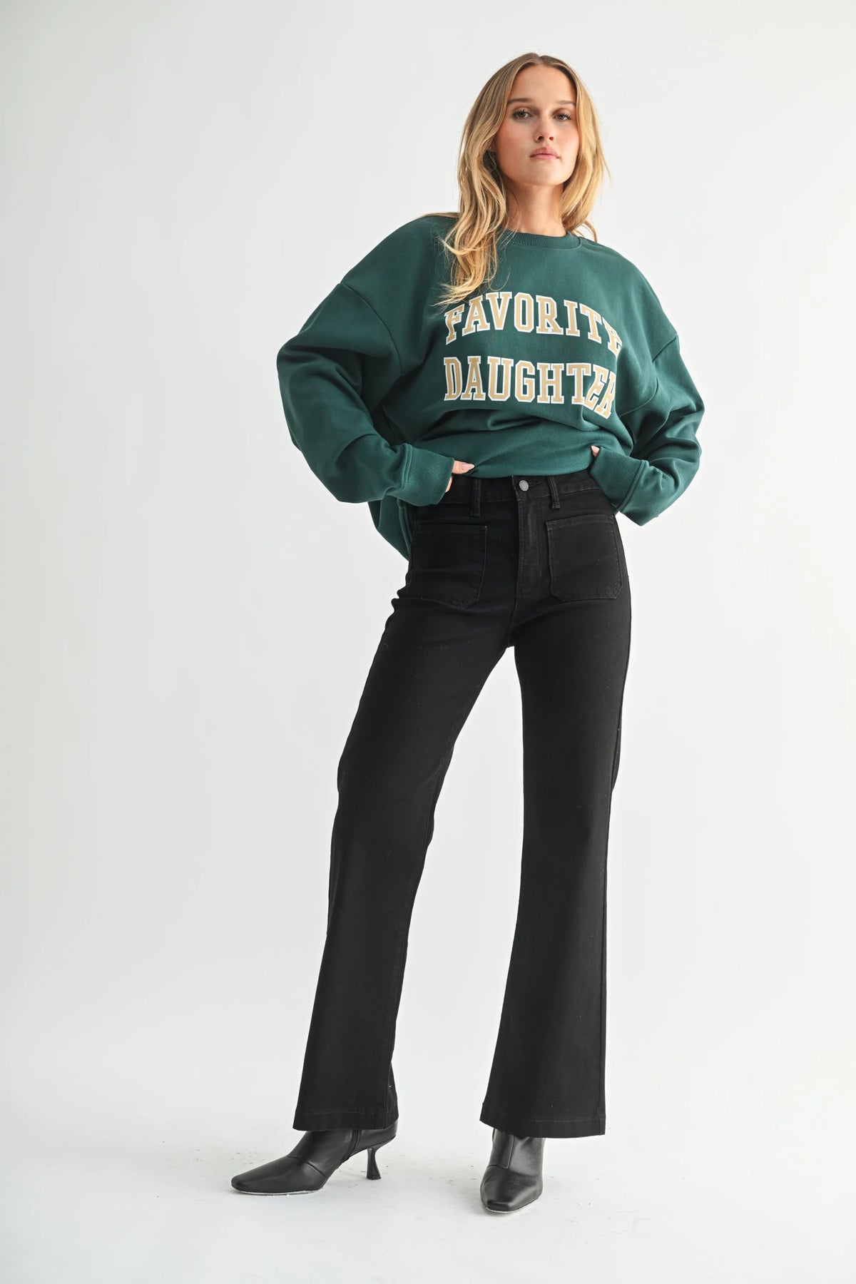 Woman wearing dark green sweatshirt with FAVORITE DAUGHTER print and MINI PATCH POCKET FLARE JEANS