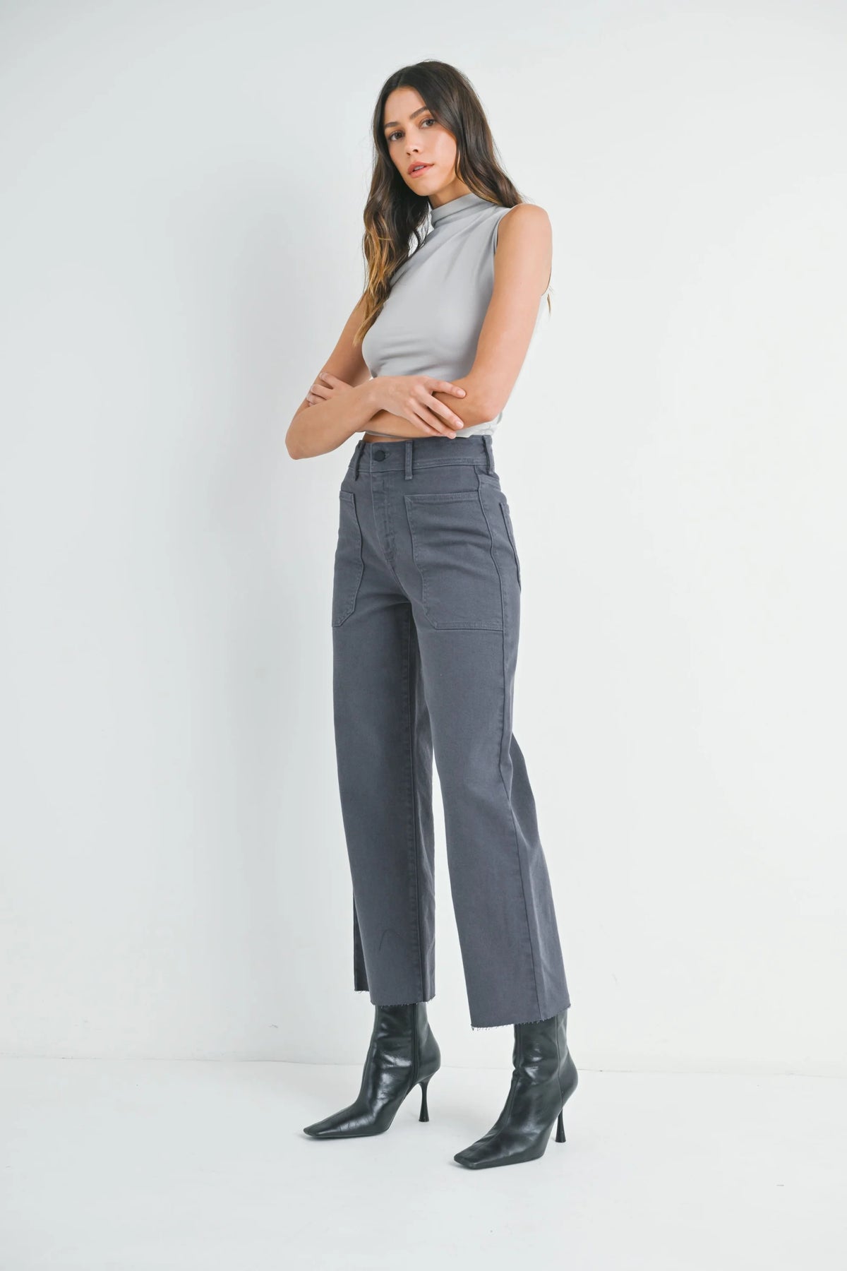 Woman modeling light gray mock-neck sleeveless top with dark gray wide leg denim trousers