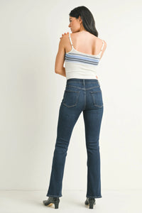 Woman modeling mid rise flare slim bootcut denim jeans with a white striped tank top