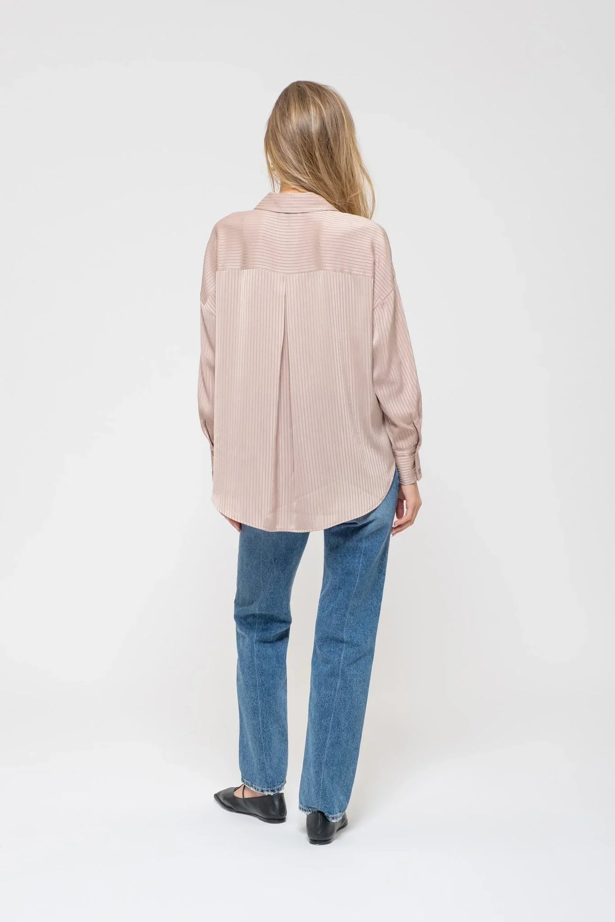 Woman in pale pink oversized shirt and blue jeans showcasing Satin Pinstripe Button Up Top