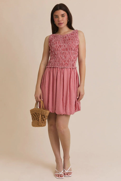 Woman wearing a red and white plaid smocked sleeveless mini dress