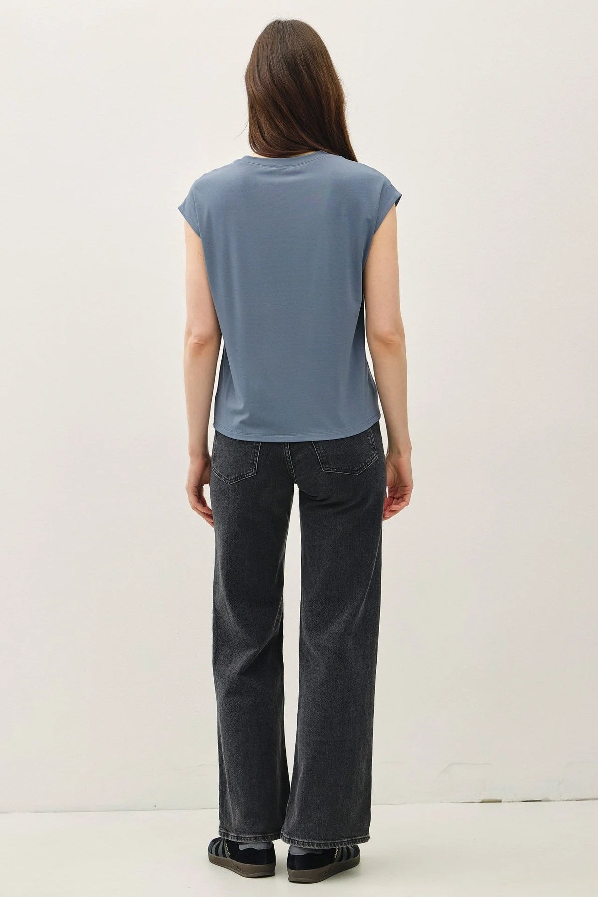 Woman wearing a blue bamboo cap sleeve basic round neck top and black wide-leg jeans