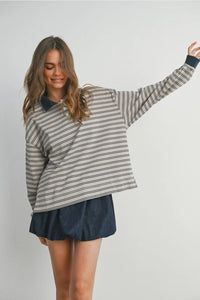 Woman wearing a striped collared long sleeve polo shirt and dark blue mini skirt