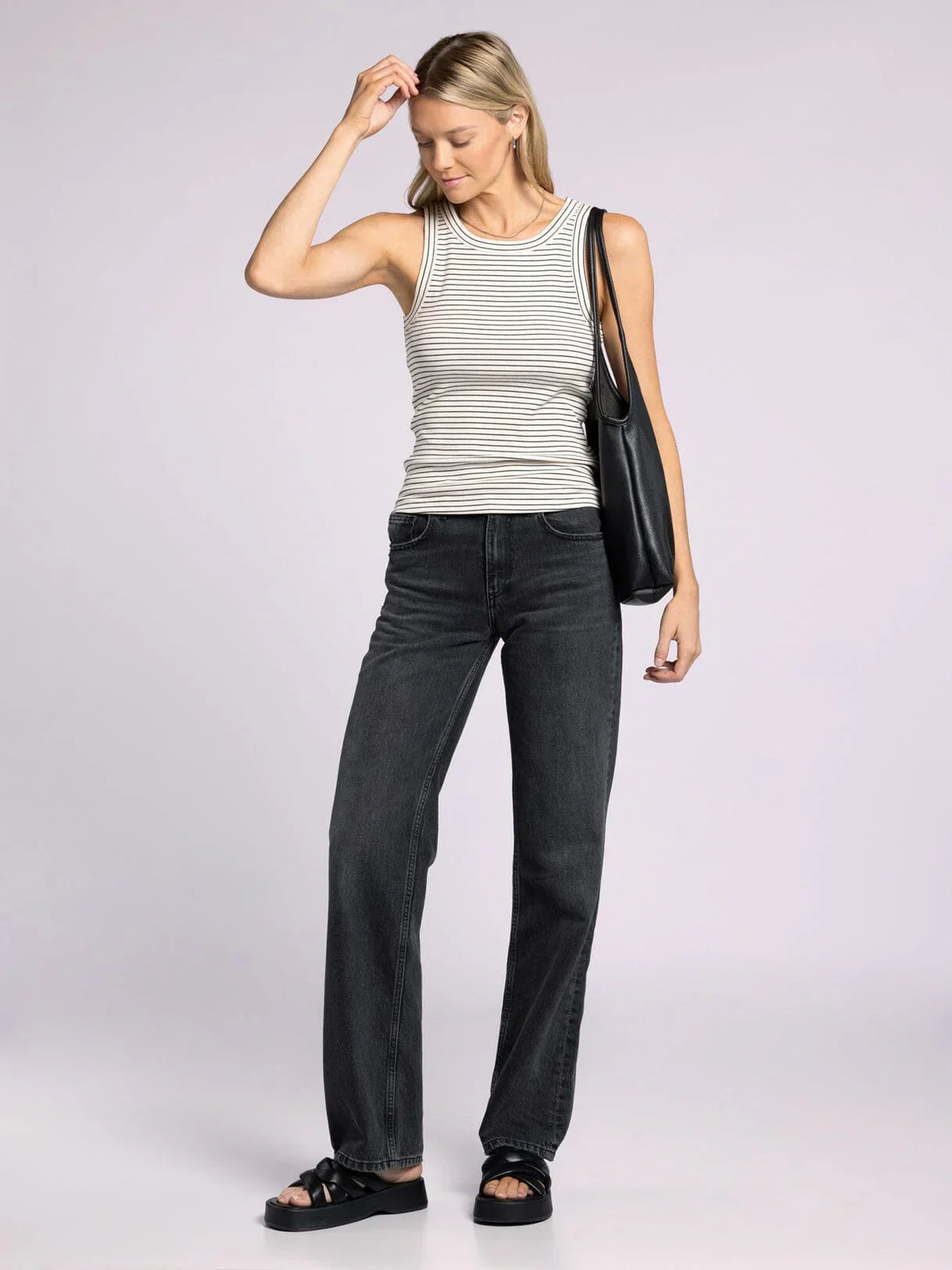 Woman wearing the Edlin Basic Tank, styled with dark jeans and a striped design