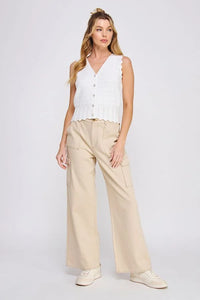 Woman wearing a pointelle knit button vest with scallop edges and a white top