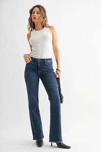 Woman in white ribbed tank top and dark wash vintage slim bootcut jeans