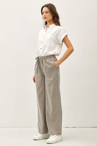 Woman wearing white shirt and gray wide leg pants with pockets, ideal for women’s boho chic clothing from Shop Daisy