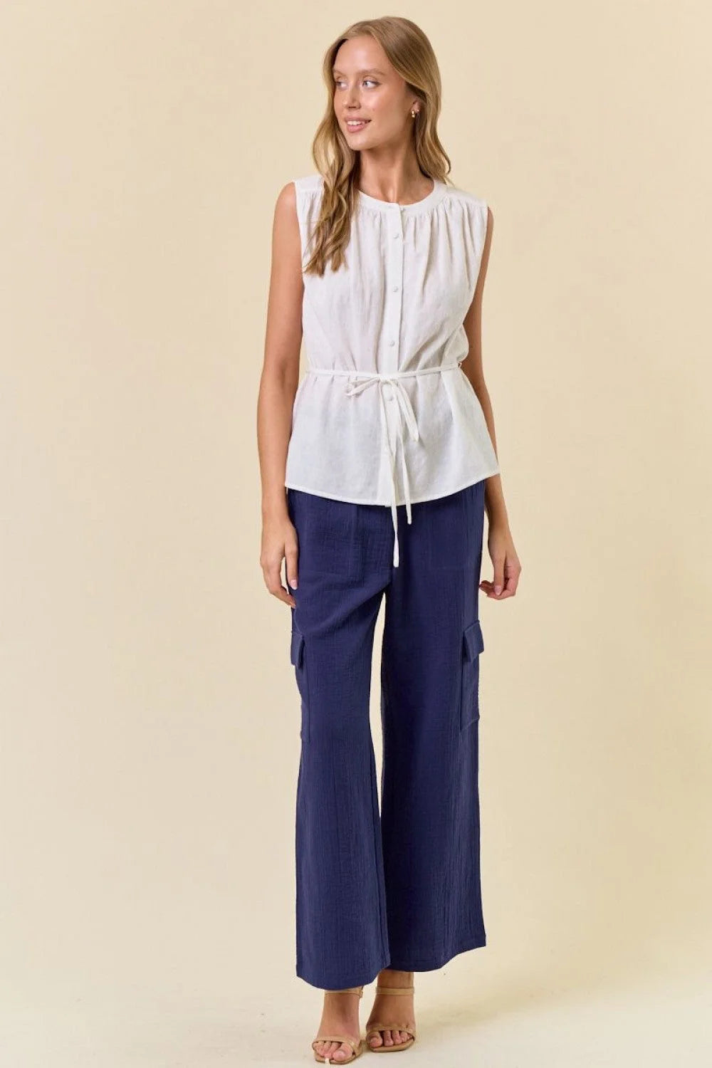 Woman wearing white sleeveless top and blue cargo pants in women’s boho chic clothing style