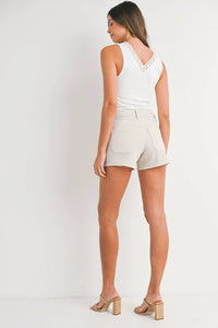 Woman wearing high rise patch pocket denim short in white tank top and beige shorts