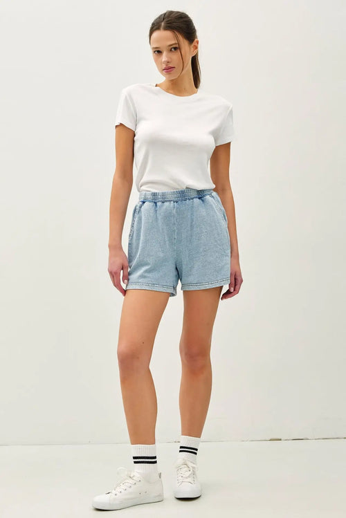 Woman in white tee and blue shorts showcasing Daisy Laneās garment dye cotton comfy shorts
