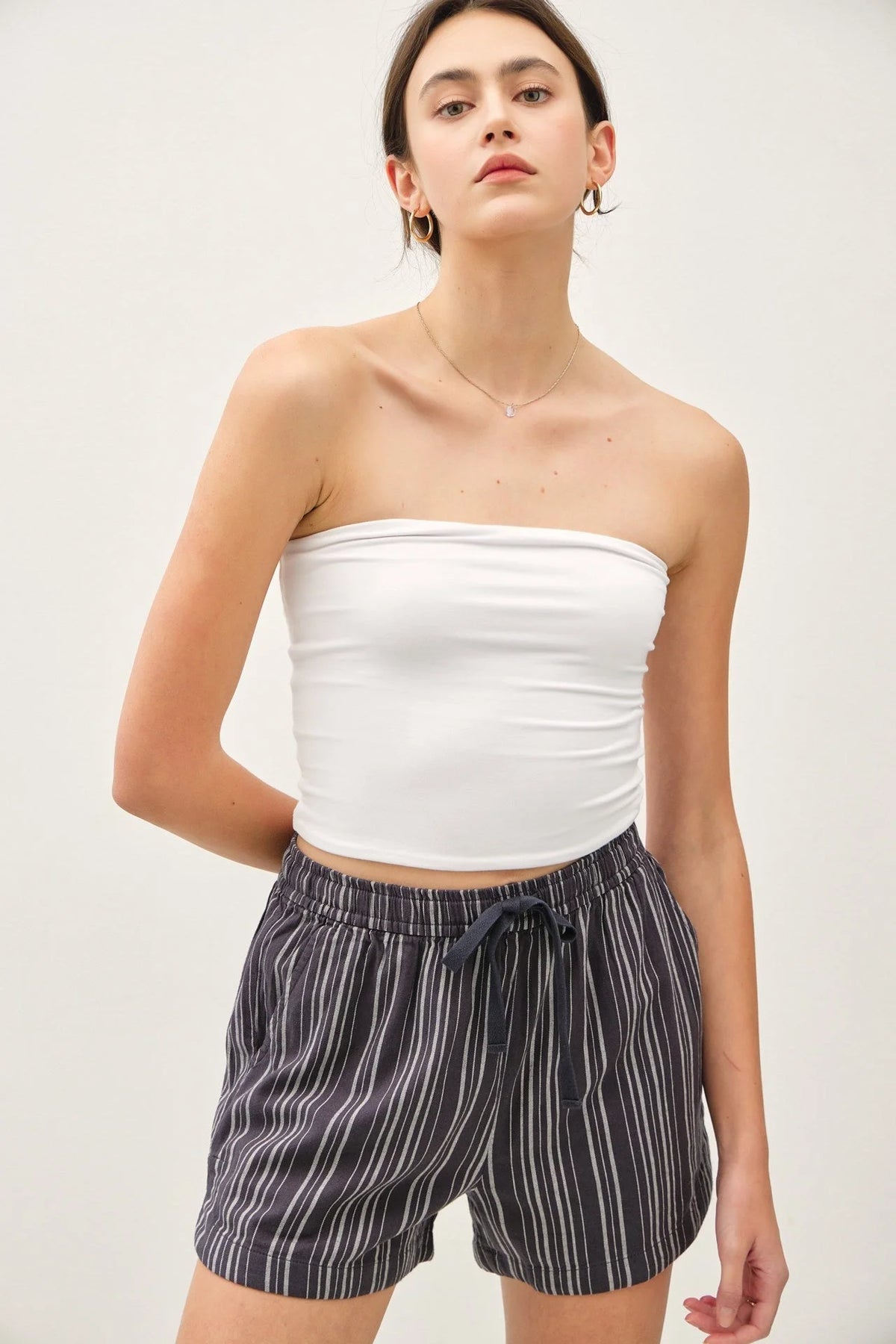 Woman wearing breezy cotton blend striped shorts and a white tube top for summer style