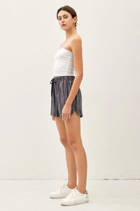 Woman wearing breezy cotton blend striped shorts and a white tube top for summer style
