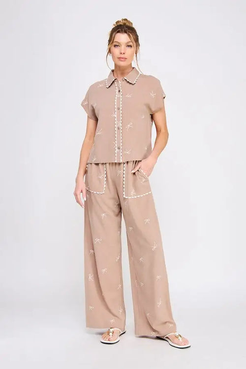 Woman wearing beige embroidered linen pants in a scallop trim pajama set for comfortable loungewear